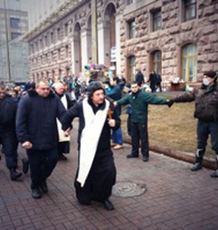 Un prete scorta i poliziotti presi prigionieri negli<br> scontri di piazza Maidan.  