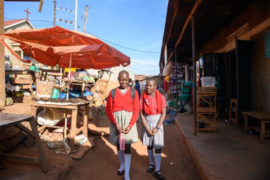 Due ragazze della Luigi Giussani tra le vie dello slum a Kampala (Foto Emmanuel Museruka/Avsi)